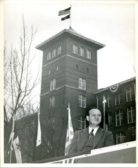 Man Seated on Podium with Firestone Mill in Background